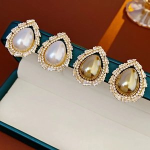 Macro view of gold teardrop pearl earrings with zircon crystals in a green jewelry box