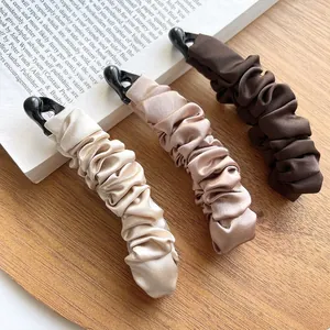 Three pleated silk fabric banana hair clips in black, champagne, and brown colors