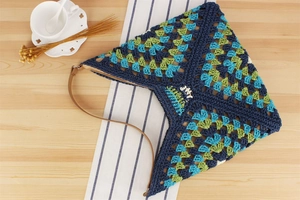 Detail of colorful crochet shoulder bag with JOY label on rustic wooden table background
