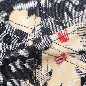 Macro shot of floral fabric texture and top button stitching on a stylish baseball cap