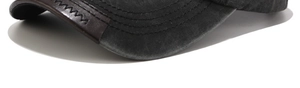 Detail of washed cotton baseball cap brim with brown leather patch and zigzag stitching