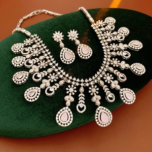 Macro shot of silver jewelry set with pink teardrop gemstones on green velvet pad