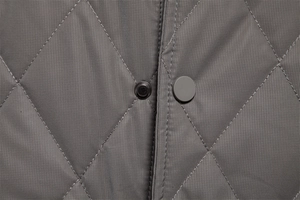 Macro detail of diamond quilted dark gray jacket with durable snap button closure