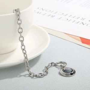 Détail d'une chaîne argentée avec pendentif en cristal gris facetté sur une tasse blanche