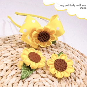 Detail of fabric sunflower hair clips and polka dot headband on straw mat surface