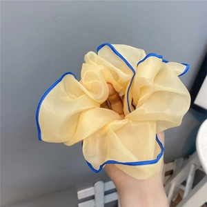 Detailed close-up of large light yellow chiffon scrunchie with blue edge stitching texture
