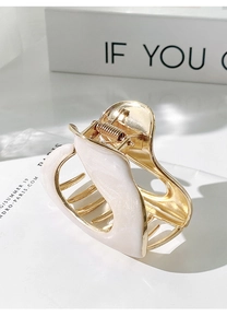 Detailed view of medium gold hair claw clip with pearlescent white wavy finish inlay