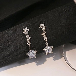 Close-up of dangling star-shaped silver earrings with cubic zirconia and fringe detail