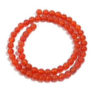 Macro shot of polished red agate round beads for jewelry making on white background
