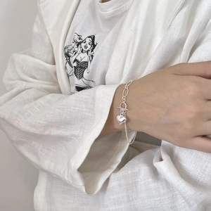 S925 sterling silver heart bracelet with OT buckle on model against white linen