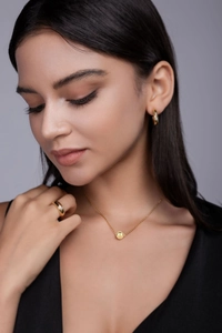 Model wearing gold teardrop necklace set with matching hoop earrings and ring