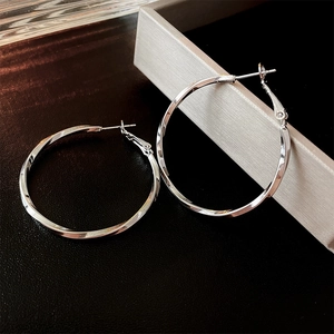 Detailed macro view of silver twisted hoop earrings featuring a unique spiral metal texture