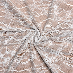 Close-up of white floral lace fabric with mesh details on an elegant open-back dress