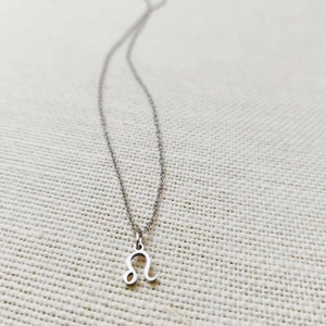 Macro shot of silver stainless steel necklace with minimalist Leo zodiac sign pendant