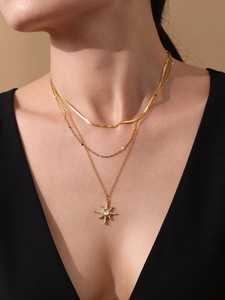 Gros plan d'un collier triple couche plaqué or 18 carats avec pendentif en étoile