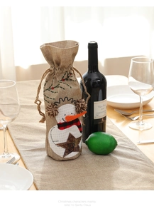 Detailed close-up of a burlap wine bottle cover with snowman embroidery and JOY lettering