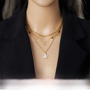 Detail of triple-layered gold plated necklace featuring shell butterfly pendants on a model
