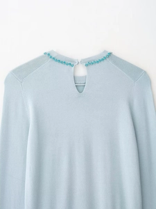 Detail of light blue knit top featuring teardrop back cutout with blue crystal embellishments