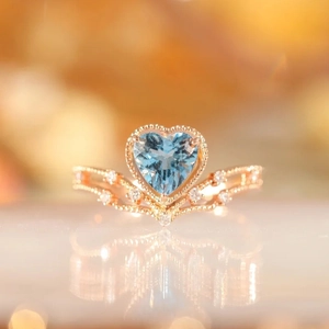 Crown-shaped rose gold ring featuring a heart-cut blue aquamarine and pavé diamonds