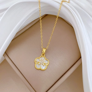 Detailed macro view of the gold flower pendant with white shell petals and sparkling crystals