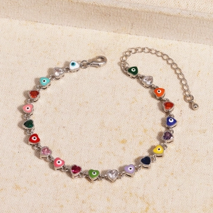 Detail of multi-colored heart-shaped evil eye charms on a silver metal chain bracelet