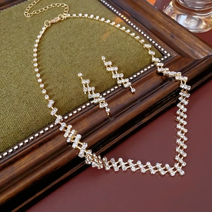 Close-up of golden geometric zigzag necklace and earring set with sparkling rhinestones