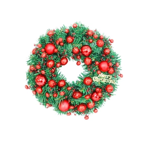 Artificial Christmas wreath with red berries, pine needles and a golden Merry Christmas sign