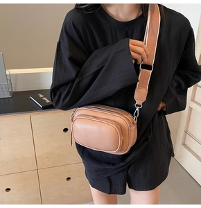 Detail of dusty pink crossbody camera bag with wide strap and pebble leather texture