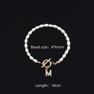 Detail of 4x6mm pearl bracelet featuring a gold toggle clasp and crystal M pendant