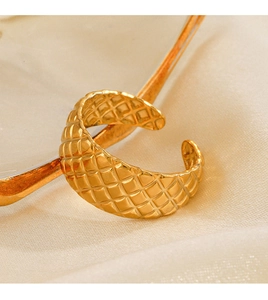 Makro-Detailansicht eines goldenen Rings mit Rautenmuster auf beigem Seidengrund