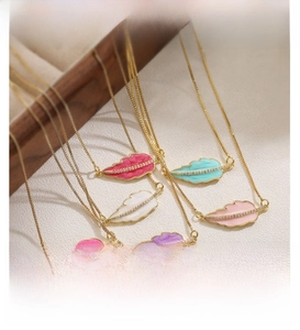 Macro shot of colorful enamel leaf pendants on gold chains with zircon accents