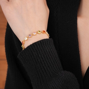 Close-up of heart-shaped colored zircon bracelet with gold-plated link chain on wrist