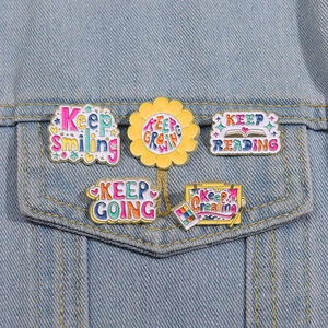 Detail showing 5 colorful inspirational enamel pins pinned on blue denim jacket pocket