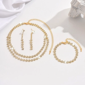 Detailansicht des goldenen Brautschmuck-Sets mit funkelnden Strasssteinen auf weißer Seide