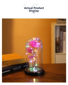Detail of pink crystal rose in glass dome with LED fairy lights on a wooden desk