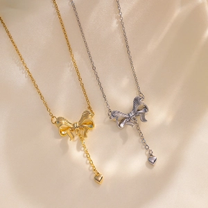 Titanium steel bowknot tassel heart necklaces in gold and silver on silk background