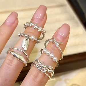 Close-up of a silver 925 ring set with a lucky tag, pearls, and bow knot designs