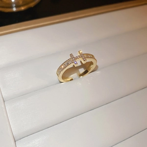 Elegant gold H-shaped ring with zircon stones on a white luxury display tray