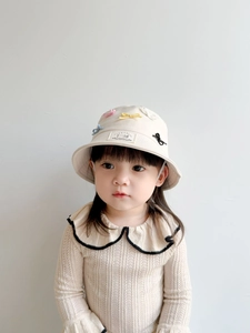 Detail of beige kids bucket hat with colorful mini bows and PIERECAT brand label