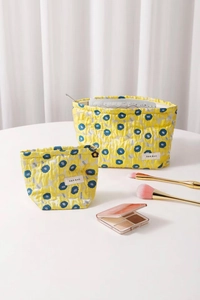Detail of yellow floral jacquard makeup bags with blue dots and brand label