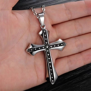 Vintage silver titanium steel cross pendant with black bead held in a person's palm