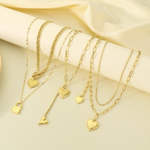 Golden titanium steel layered necklace set with heart and padlock pendants on a display