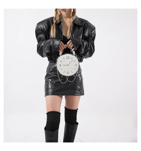 Detail of white round clock-shaped PU leather handbag with silver chain and metal handle