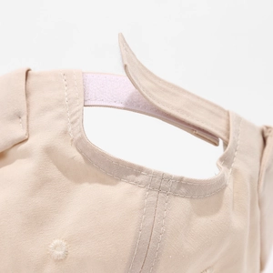 Détail de la sangle velcro réglable sur une casquette bébé en coton beige poli