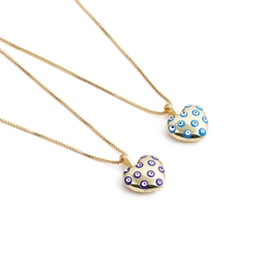 Macro view of gold heart pendants with blue evil eye patterns on fine box chains