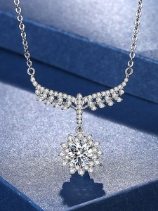 Macro shot of sunburst flower pendant with sparkling cubic zirconia on a blue velvet box