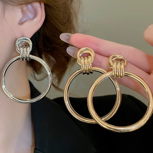 Detaillierte Ansicht übergroßer verknoteter Metallohrringe in Gold und Silber-Finish