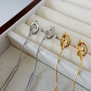 Detail of gold and silver knot earrings with snake chain tassels in a jewelry box