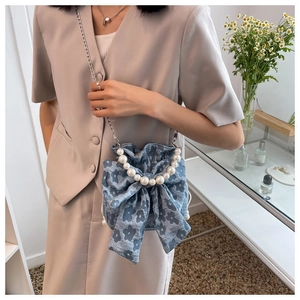Detail of floral blue crossbody bag with elegant pearl handle and silver metal chain