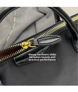 Detail of high-density nylon bucket bag featuring a gold metal zipper and black leather tab
